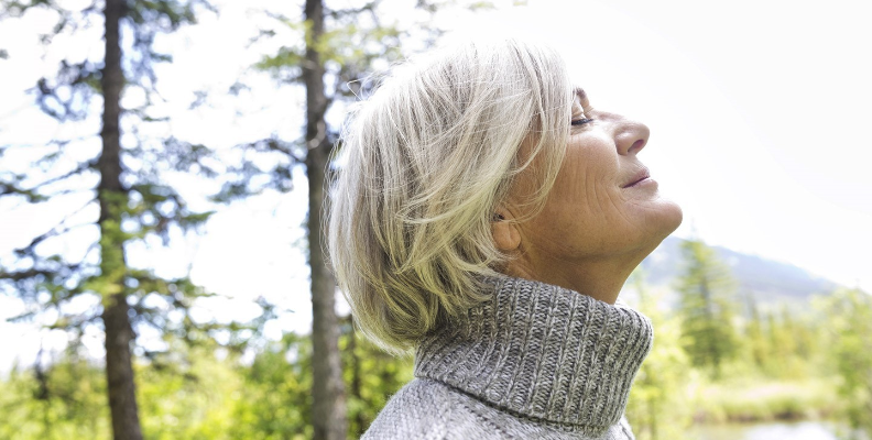 Woman practicing breathing techniques outdoors. One way to promote deeper breathing and better health is exhaling fully.