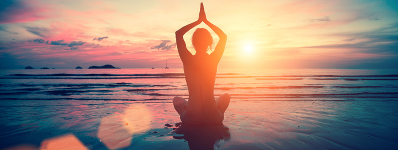 woman in yoga pose on a beach at sunset