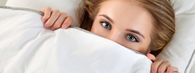 Woman peeking out from under the covers in bed