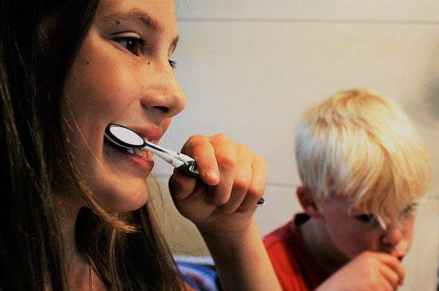 woman and boy brushing their teeth together