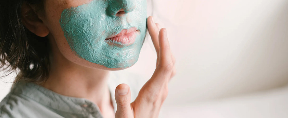 Woman putting on a creamy facial mask.