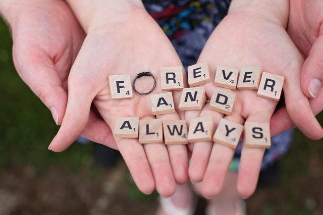 Man and woman hands holding Scrabble tiles arranged to say Forever and Always. 