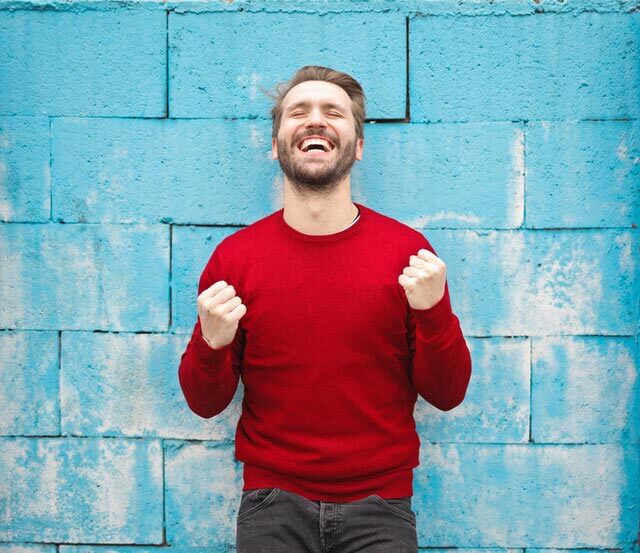 Man in red sweater looking joyful.